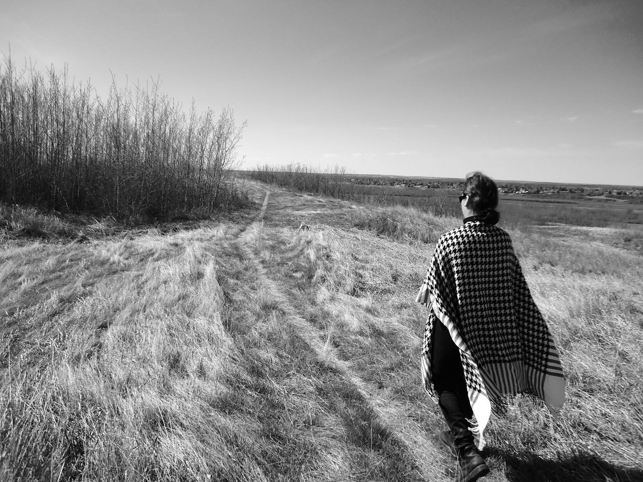 Woman with long checked cape behind her on a field