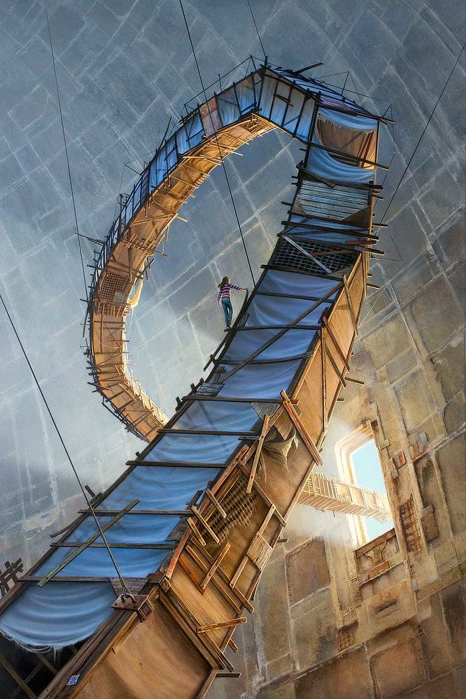 A winding shaft, built of makeshift boards and other found materials, climbs up a seemingly endless stone chamber. Fabric, mostly intact, stretches across the frame of the boards creating a contained space inside, but a young woman in a red striped shirt and blue jeans stands astride the outside peering over to where light spills through an opening in the massive stone facade. The structure continues upward supported by cables at many points before it corkscrews over—like the arc of a roller coaster but far less structurally sound—and winds through an opening in the stone wall out to blue sky.