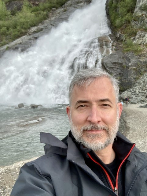 Larry Cornett in front of waterfall in Alaska