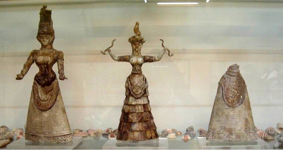 Museum display of two Minoan Snake Goddess faience figurines along with a third figurine of just the lower, skirt-covered half of a figurine with unknown top and torso