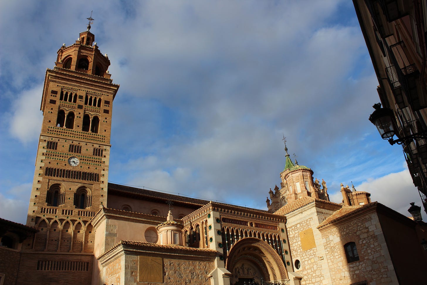 A Mudéjar style cathedral sits below a brooding cloudy sky in Teruel.