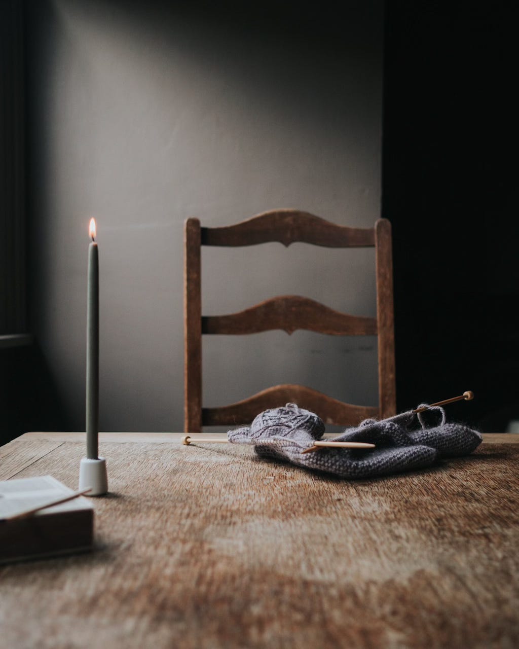 Candle, matchbox and knitting project on a wooden table 