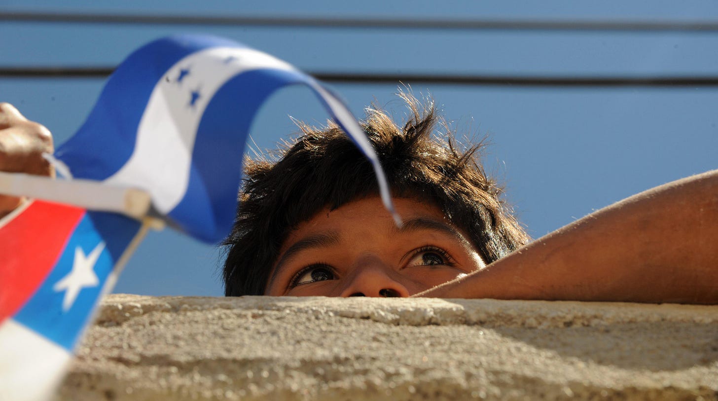 A young boy holds a Chilean and Honduran flag. (Orlando Sierra/AFP via Getty Images.)