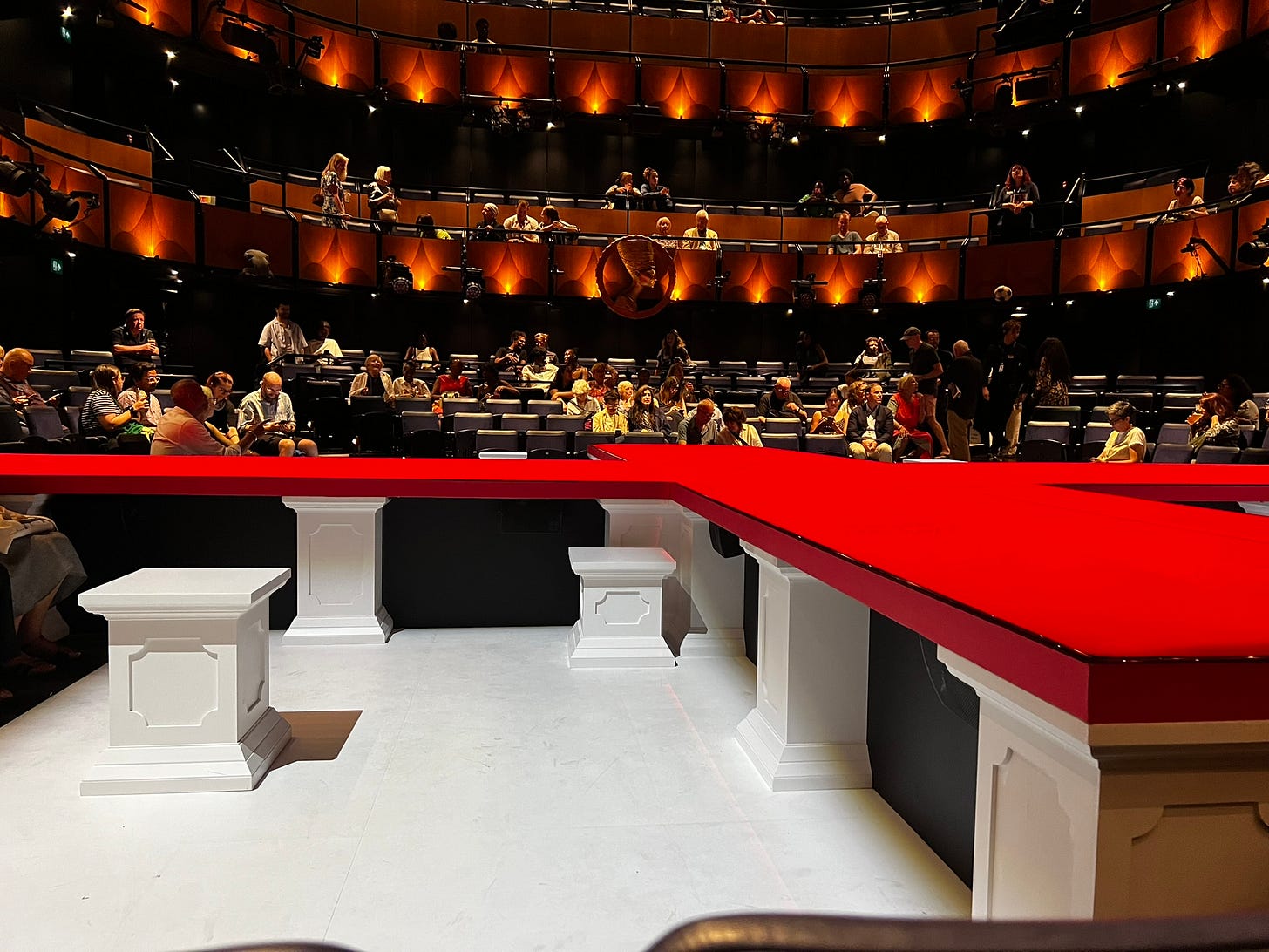 The empty stage for Death of England: Michael, before the start of the performance. The stage is clad in red and is laid out in a cross formation, with the audience on all four sides