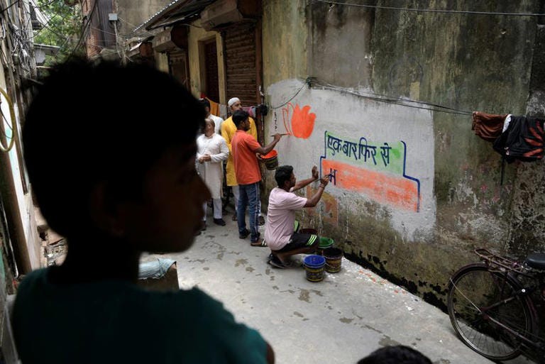 Workers of India's ruling BJP paint slogans and party symbol on a wall during an outreach program in Kolkata