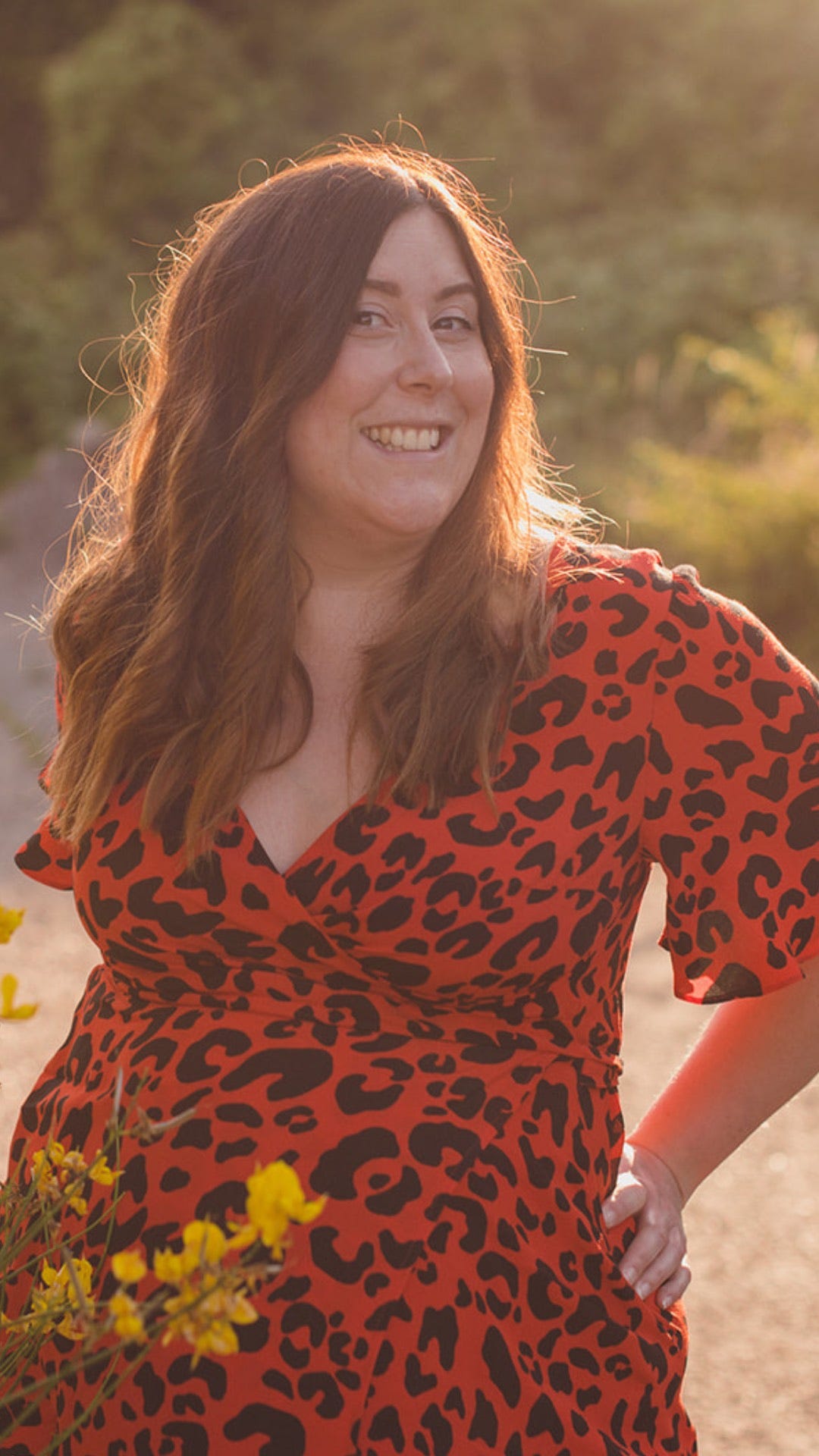 Headshot of today's guest, Jeanette, wearing a red and black leopard print dress outdoors