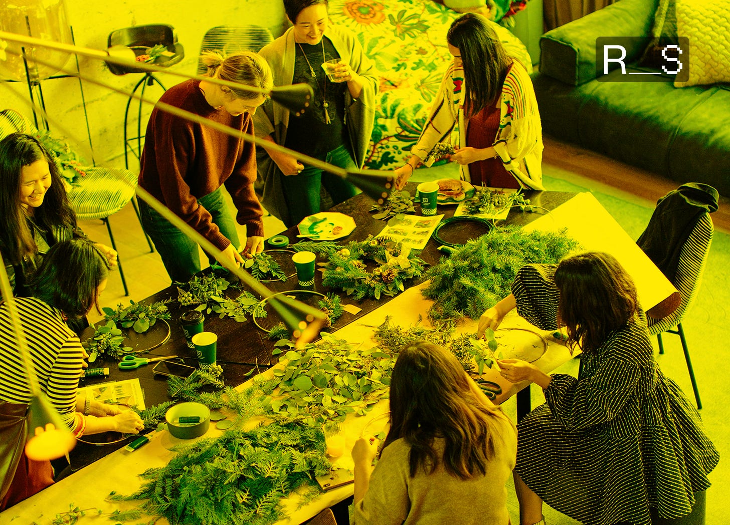 A diverse group of individuals, likely adults, engaged in a hands-on workshop, arranging green foliage and herbs on a long table. They are collaborating, learning, and sharing skills in a communal setting, reflecting the community and sustainability focus of lefty preppers. A diverse group of individuals, likely adults, engaged in a hands-on workshop, arranging green foliage and herbs on a long table. They are collaborating, learning, and sharing skills in a communal setting, reflecting the community and sustainability focus of lefty preppers.