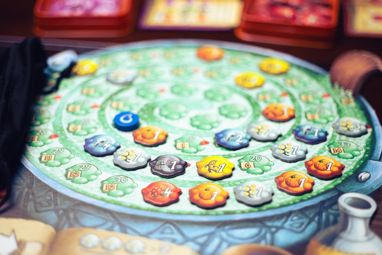 The board game The Quacks of Quedlinburg on a table. The player board, shaped like a cauldron, features many pieces placed in a spiral on the board.