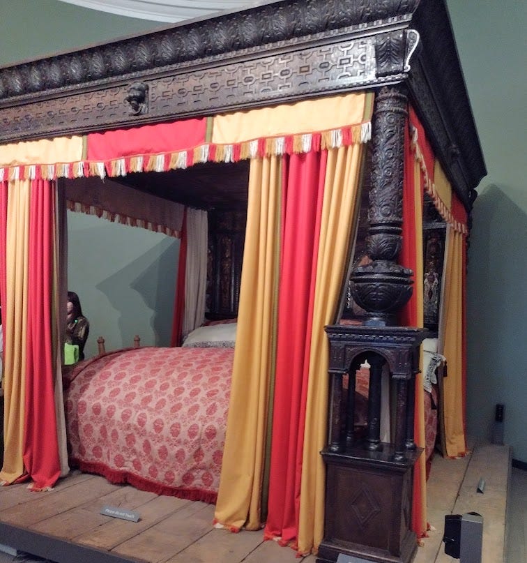 Large wooden four-poster bed with curtains