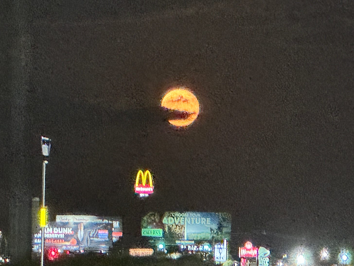 Harvest moon above frontage road streetscape