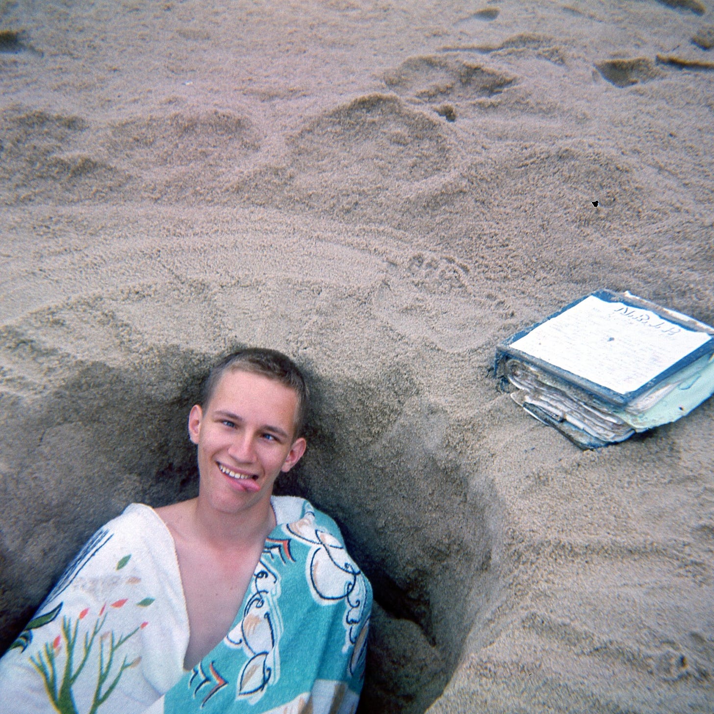 John in a hole in the sand with a towel