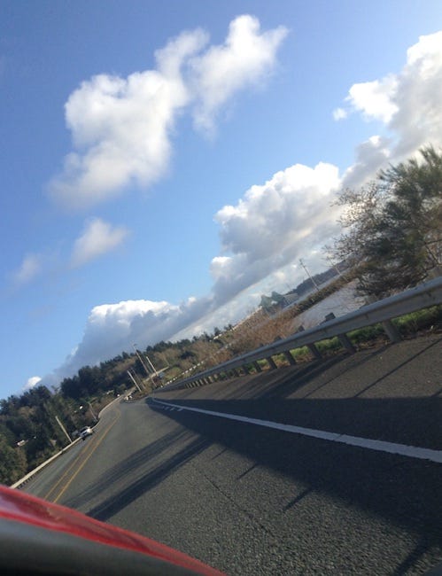 A wonky picture, taken from the car, of a bridge, under cloudy blue skies