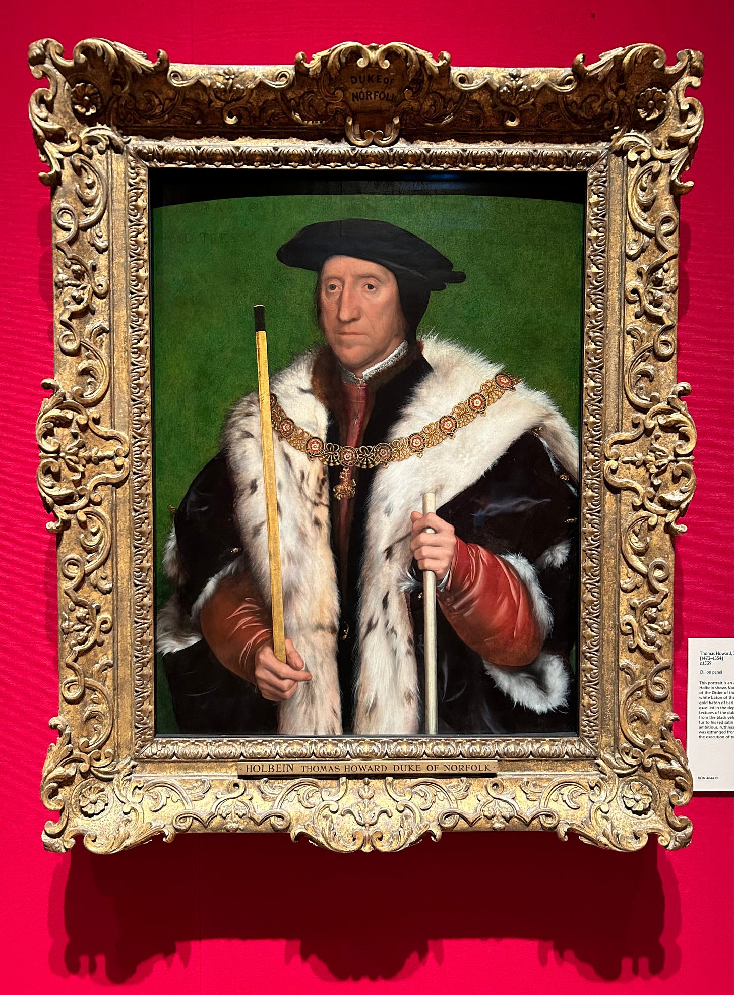 A painting of Thomas Howard, Duke of Norfolk. He is holding two staffs of office, dressed richly in furs and a gold chain. He has a thin face.