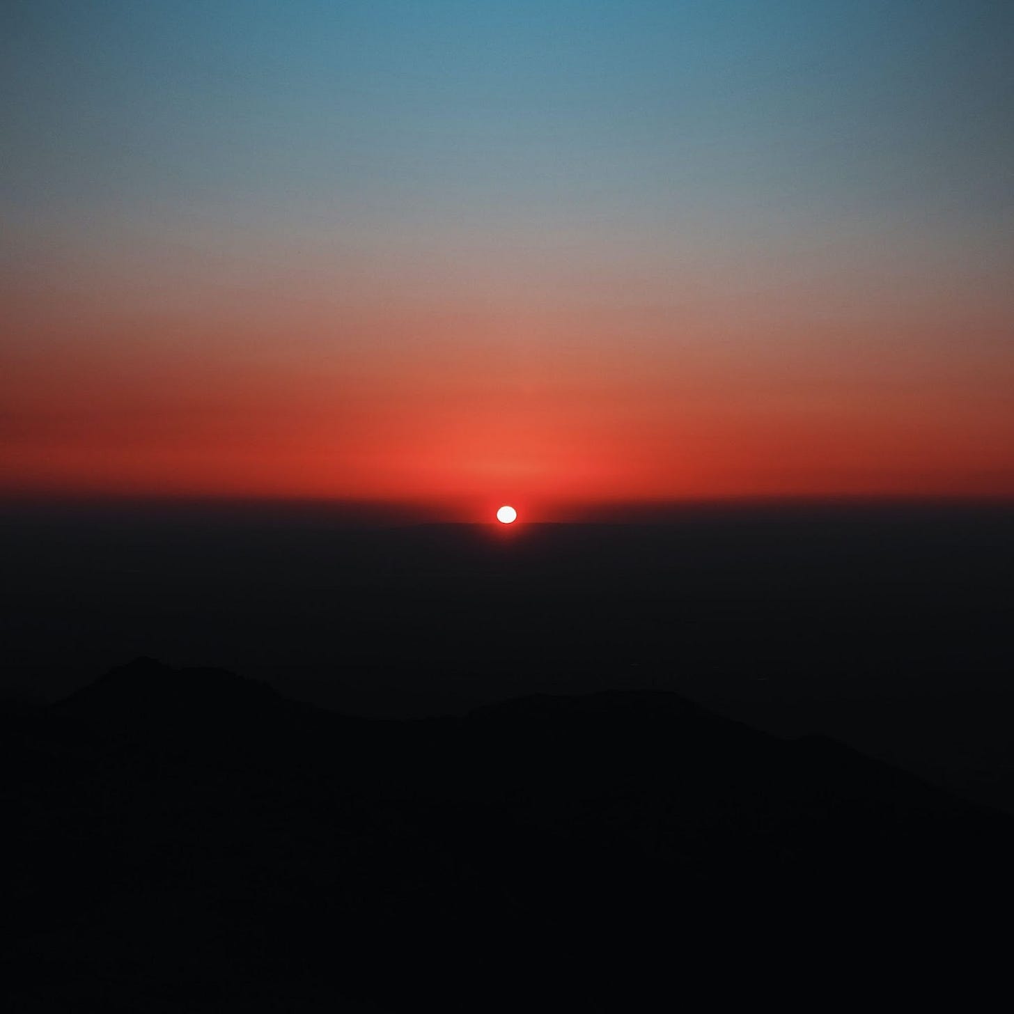 A sunrise over a pitch black land, fading up into a red and then blue sky. A sunrise over a pitch black land, fading up into a red and then blue sky.