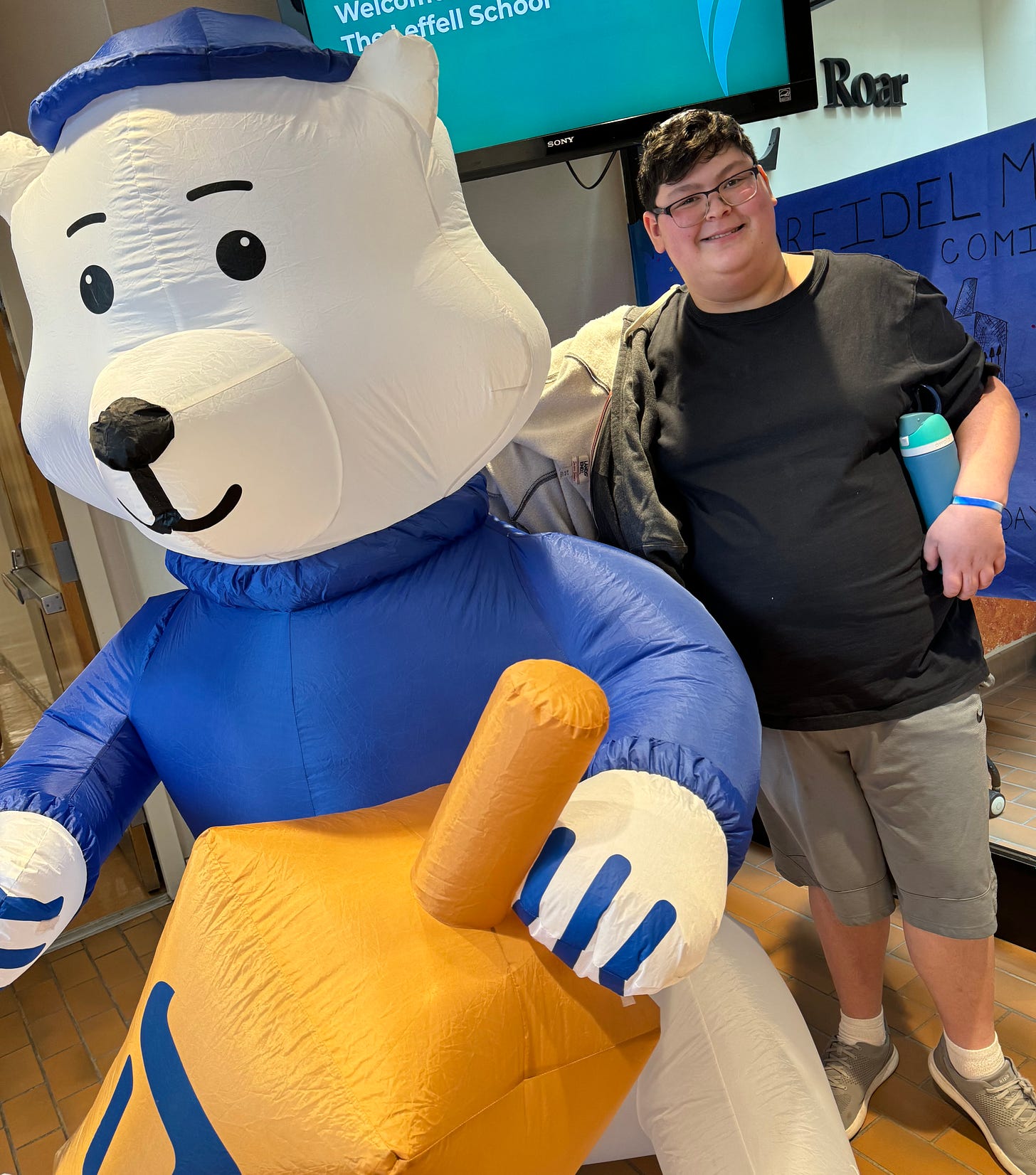 Rafi, the author, is a white-skinned teenager wearing glasses. He poses with a large inflatable Hanukkah bear.