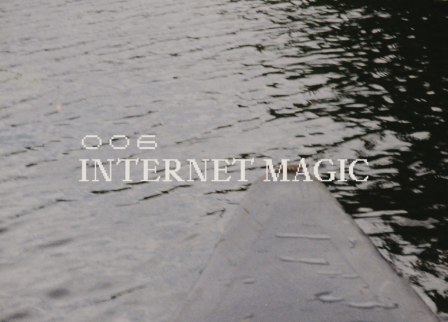 POV tip of a canoe on a dark, rippling lake.. Distorted film quality, reads "006 Internet Magic" in a pixelated serif font.