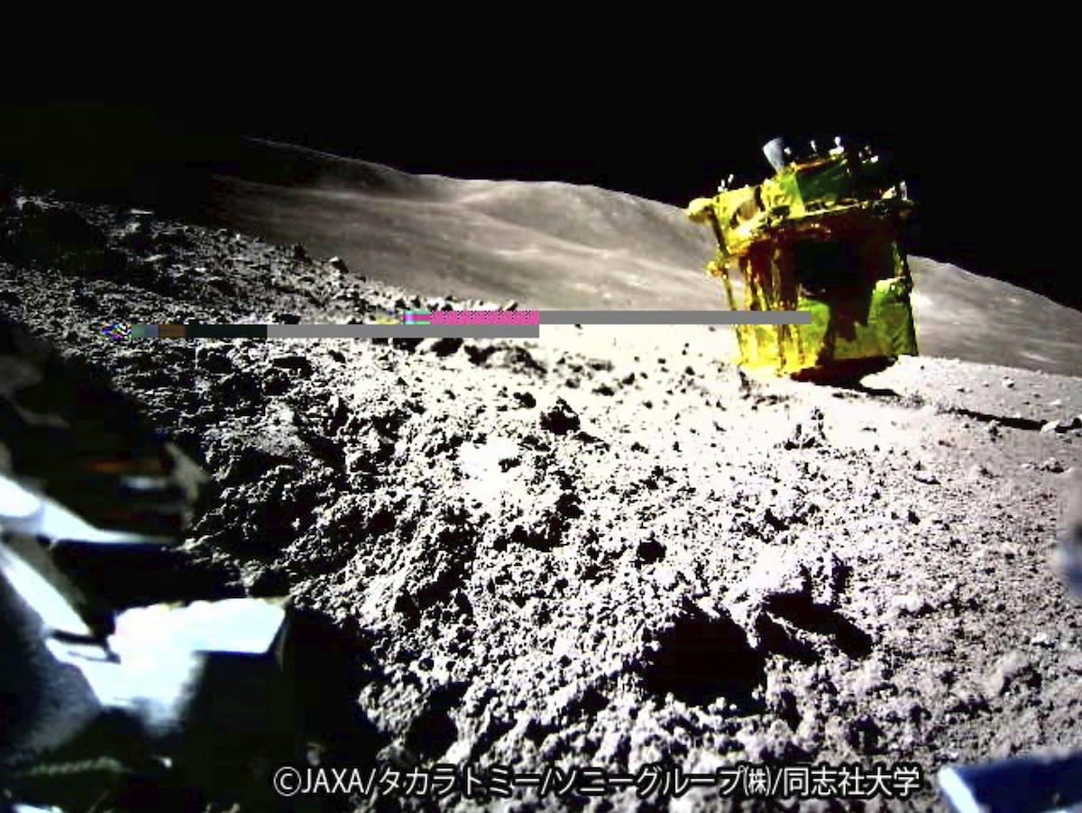 A space probe is landed on the rocky surface of an asteroid, with sunlight casting shadows.