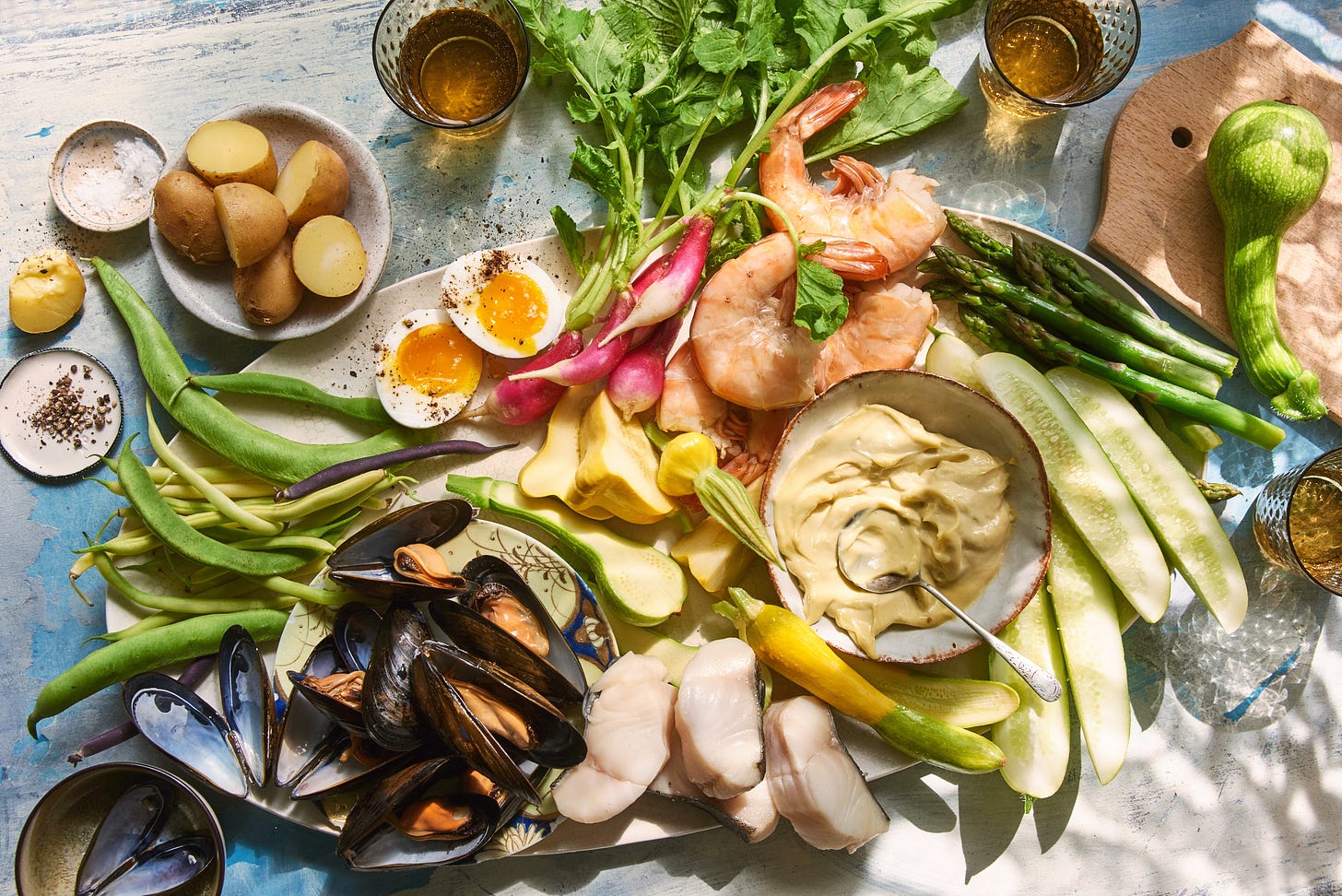 a tray of seafood and vegetables all dappled in sunlight