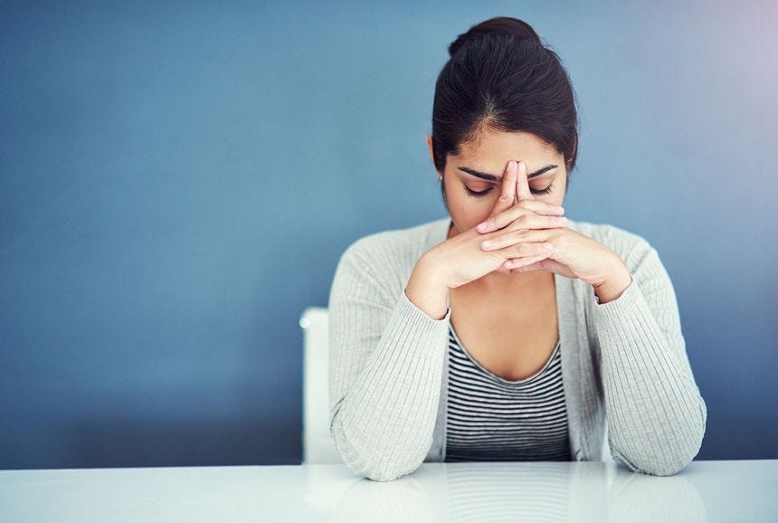 Woman who has just been fired sitting with her head in her hands.