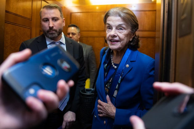 Dianne Feinstein speaking with reporters while standing in an elevator.