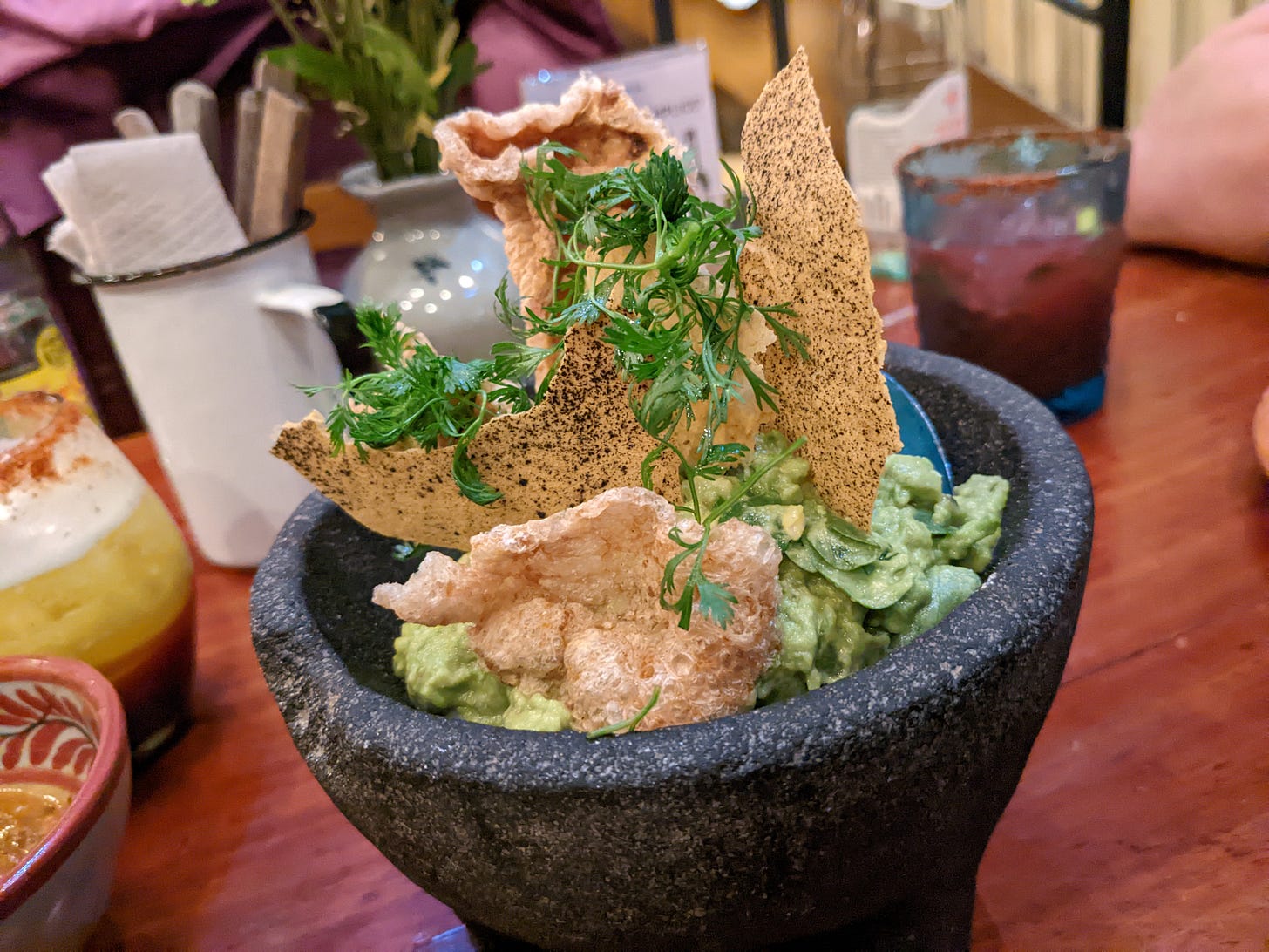 guacamole with herbs and chips in a stoneware serving dish at Fonda Fina