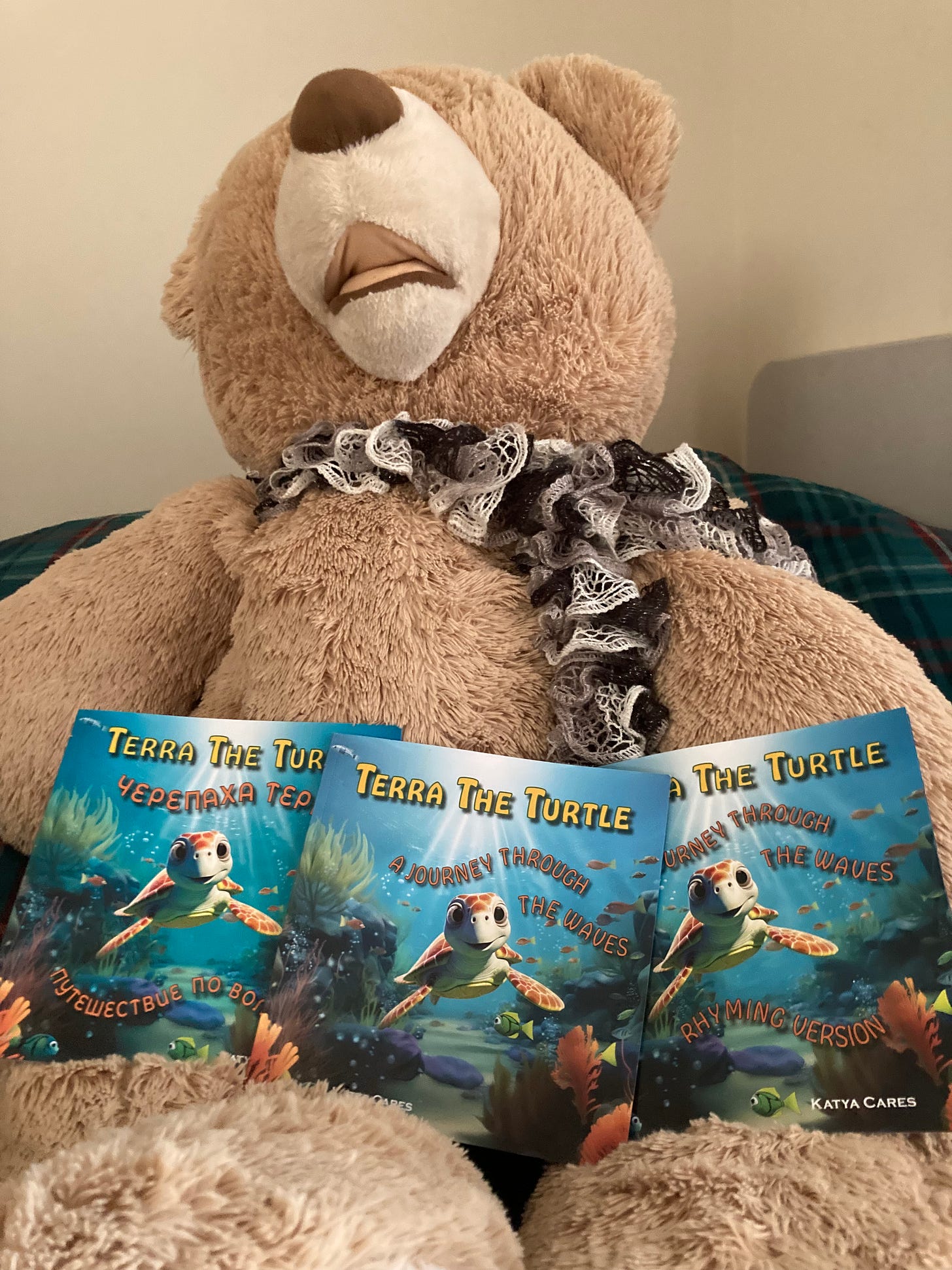 A large toy bear holding the 3 books we published