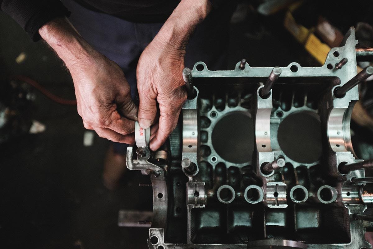 Closeup of a mechanic's hands adjusting part of a car engine.