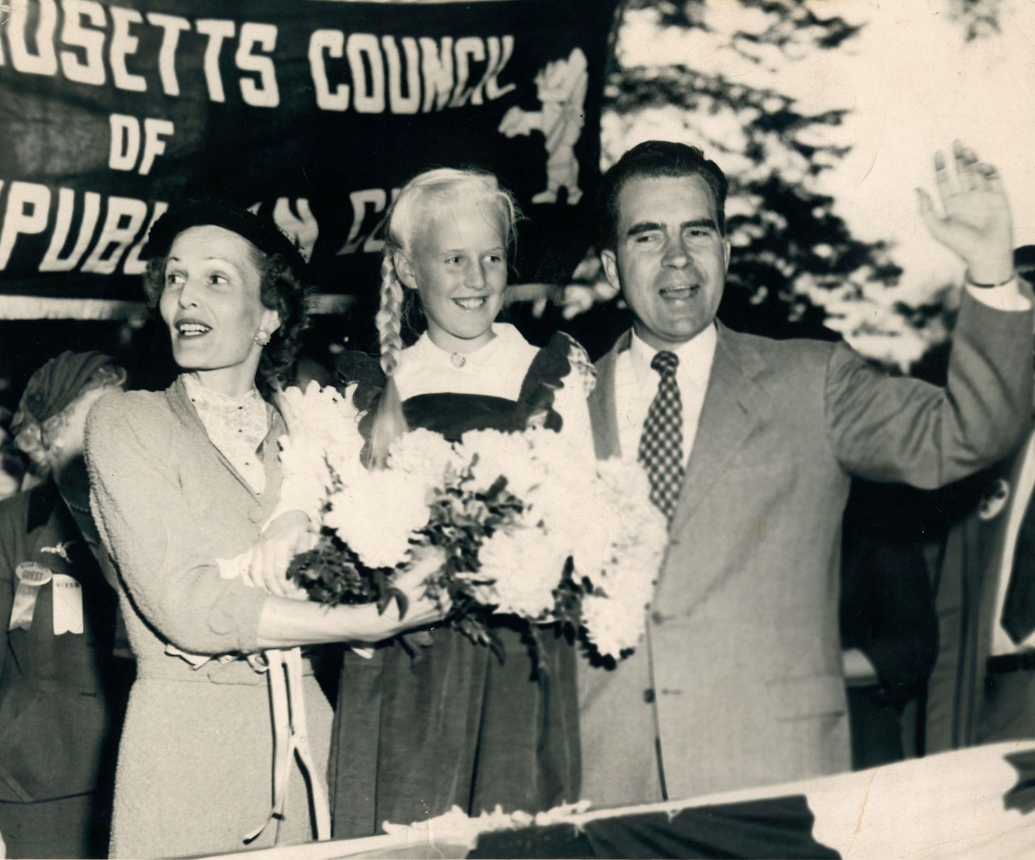 A slightly yellowed black-and-white photo of a smiling blonde ten-year-old girl holding a bouquet of flowers between Pat and Richard Nixon.