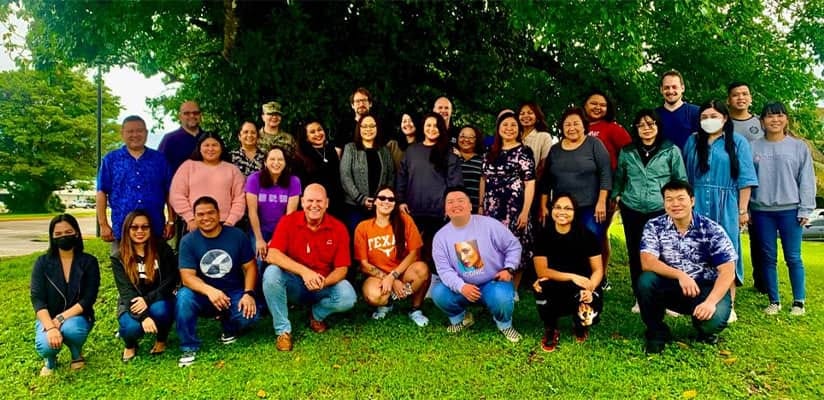 This color photograph shows 29 participants in "Towards a More Perfect Union's" October 2022 seminar and facilitator Dr. Kirk Johnson posing on the University of Guam's campus during their last day together. This color photograph shows 29 participants in "Towards a More Perfect Union's" October 2022 seminar and facilitator Dr. Kirk Johnson posing on the University of Guam's campus during their last day together.