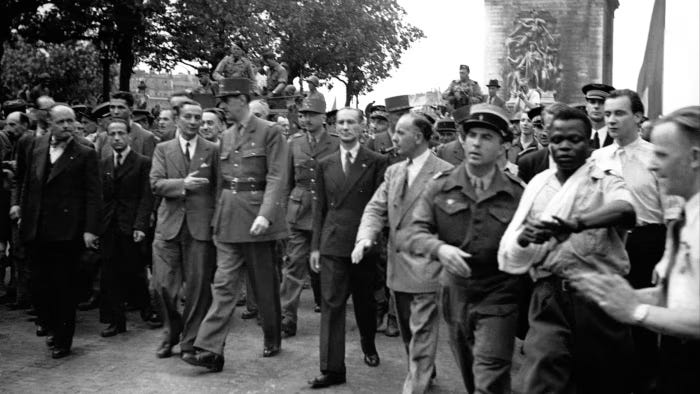 General Charles de Gaulle walks down the Champs Élysées on August 26 1944. Georges Dukson marches to his left, raising an arm