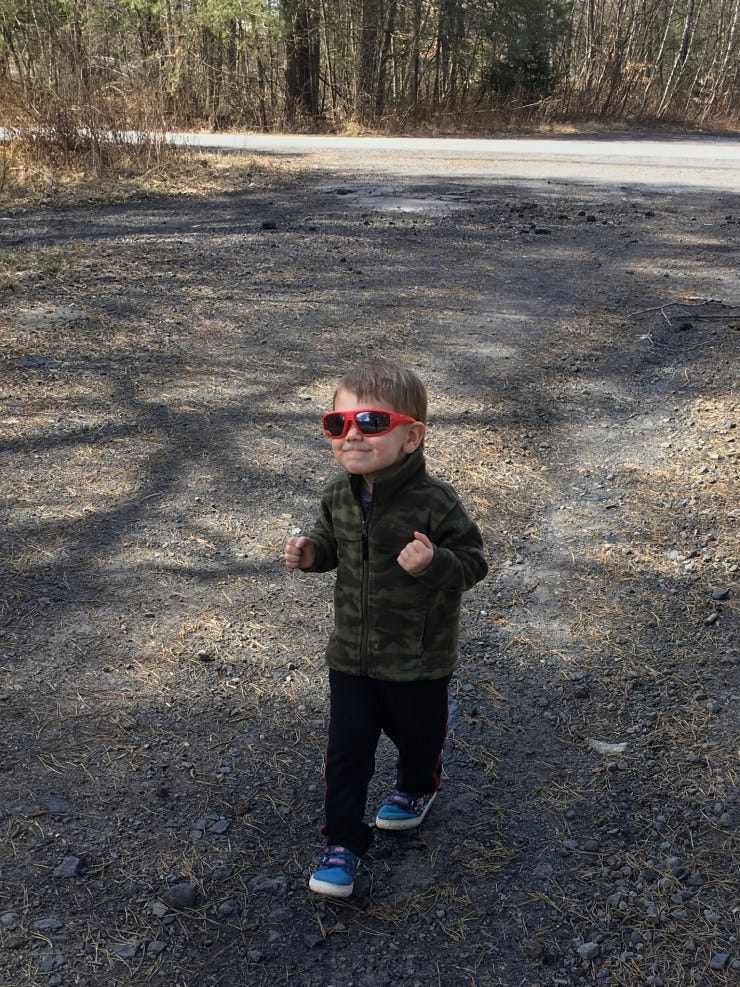 Little boy in sunglasses walking on a trail