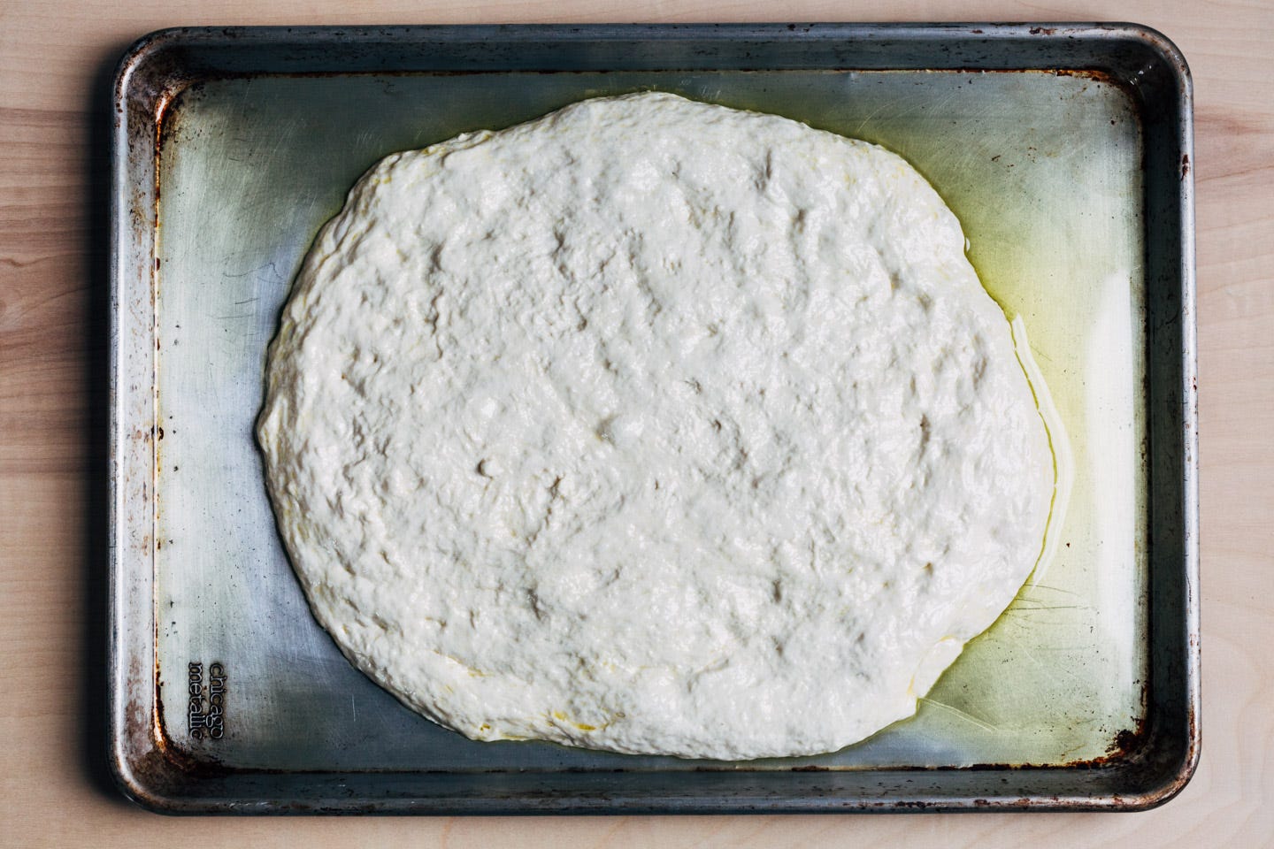 An oiled baking sheet with focaccia dough.