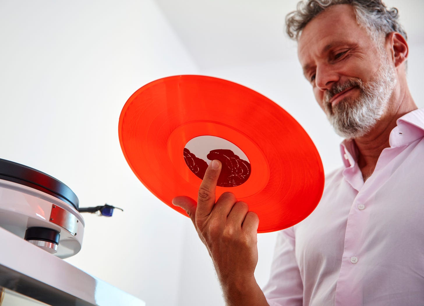 A man holds a red vinyl record.