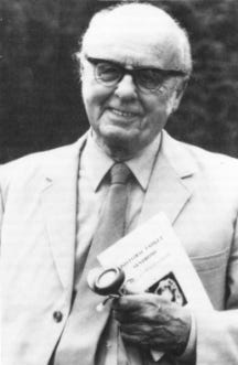 Black and white photo of Melvin Ramsay, a smiling white man in his sixties or seventies, dressed in a light-coloured suit, holding a stethescope and a copy of his book 'Myalgic Encephalomyelitis and Postviral Fatigue States'. 