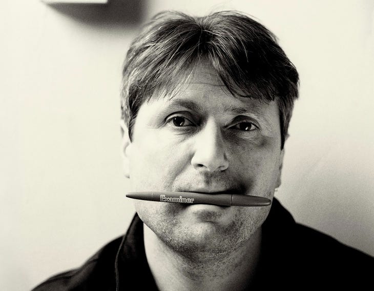 A photo of Simon Armitage with a pen in his mouth