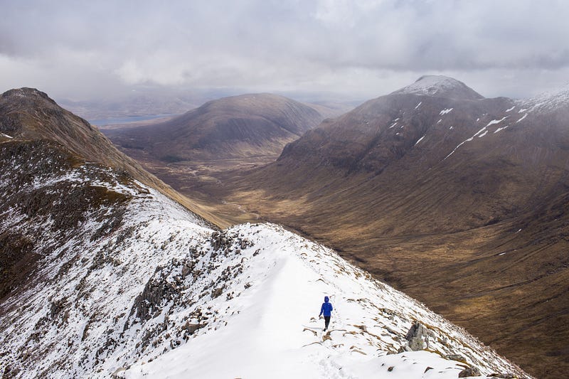 A lone hillwalker on snow covered hill