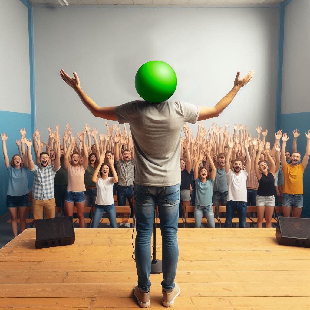 Photo from behind a man dressed in a t-shirt and jeans standing on a small stage receiving praise from a small simple room full of happy people standing, cheering, and raising their hands. Instead of a head, the man has a volleyball-sized basic bright green sphere where his head would be.