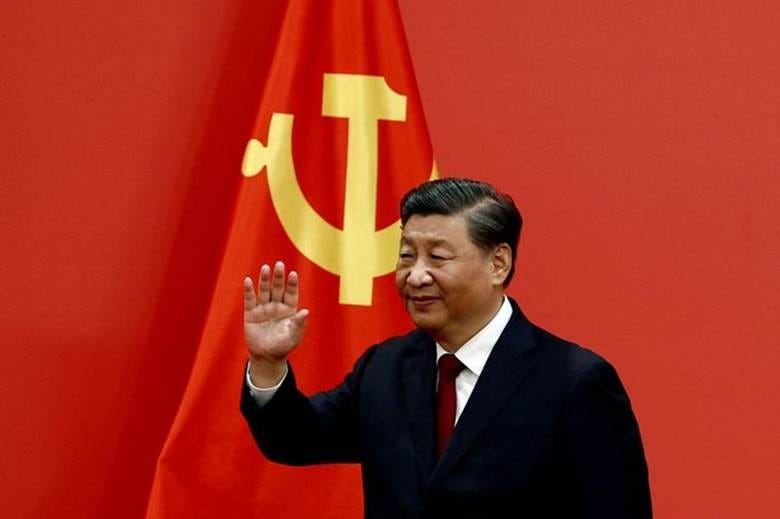 A person in a suit waving in front of a flag

Description automatically generated