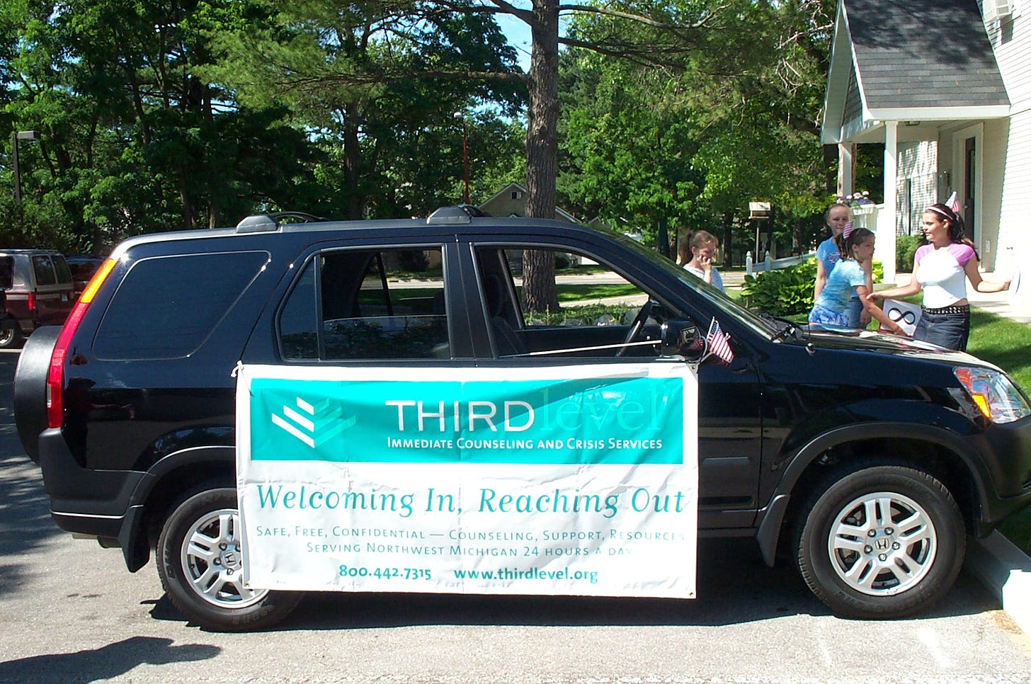 A blue SUV with a Third Level Immediate Counseling and Crisis Service banner on it.s