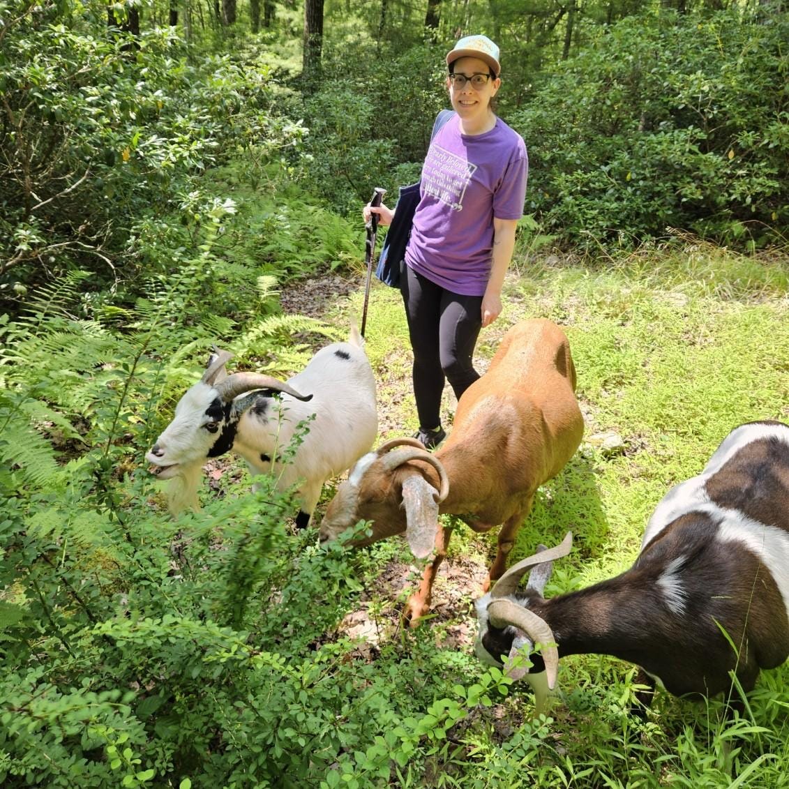 rachel kramer bussel standing with 3 goats in the woods