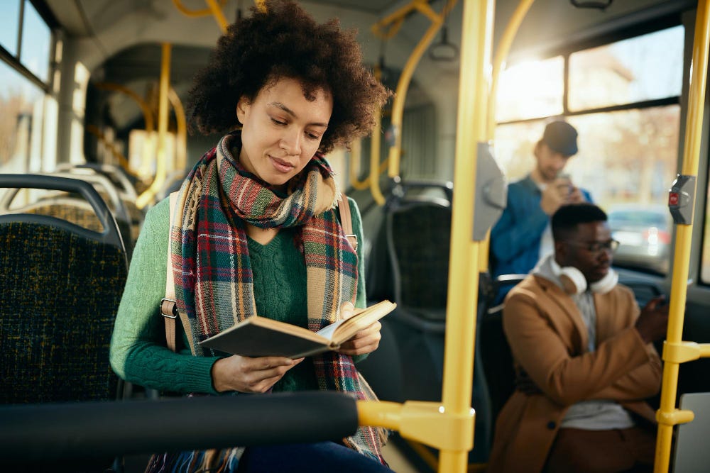 Young lady reading a book on a train.