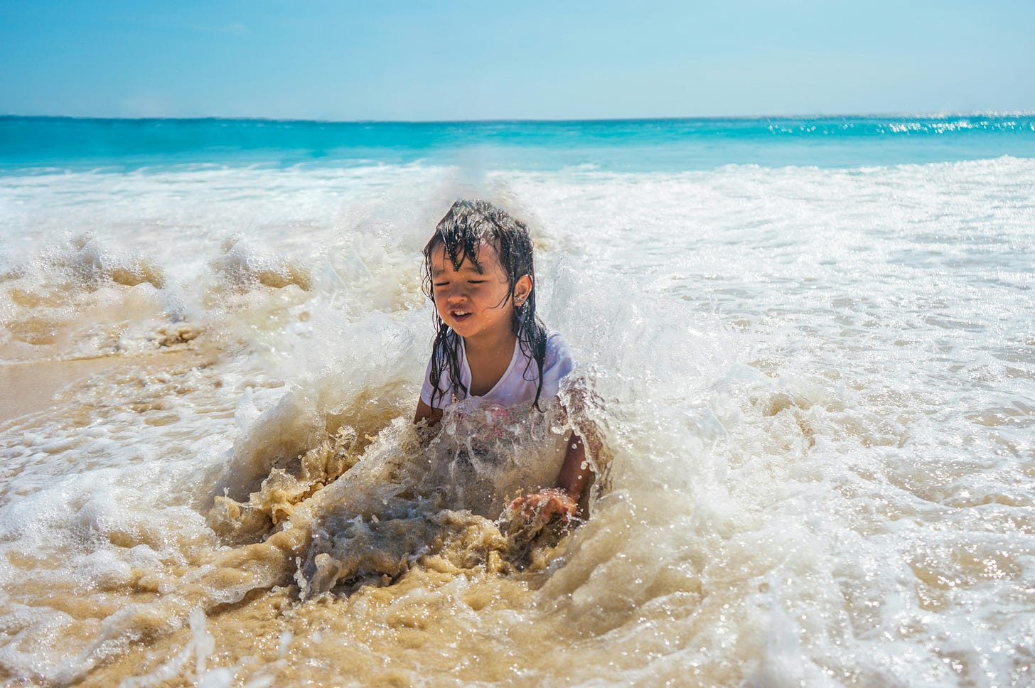 Little girl sitting in the waves