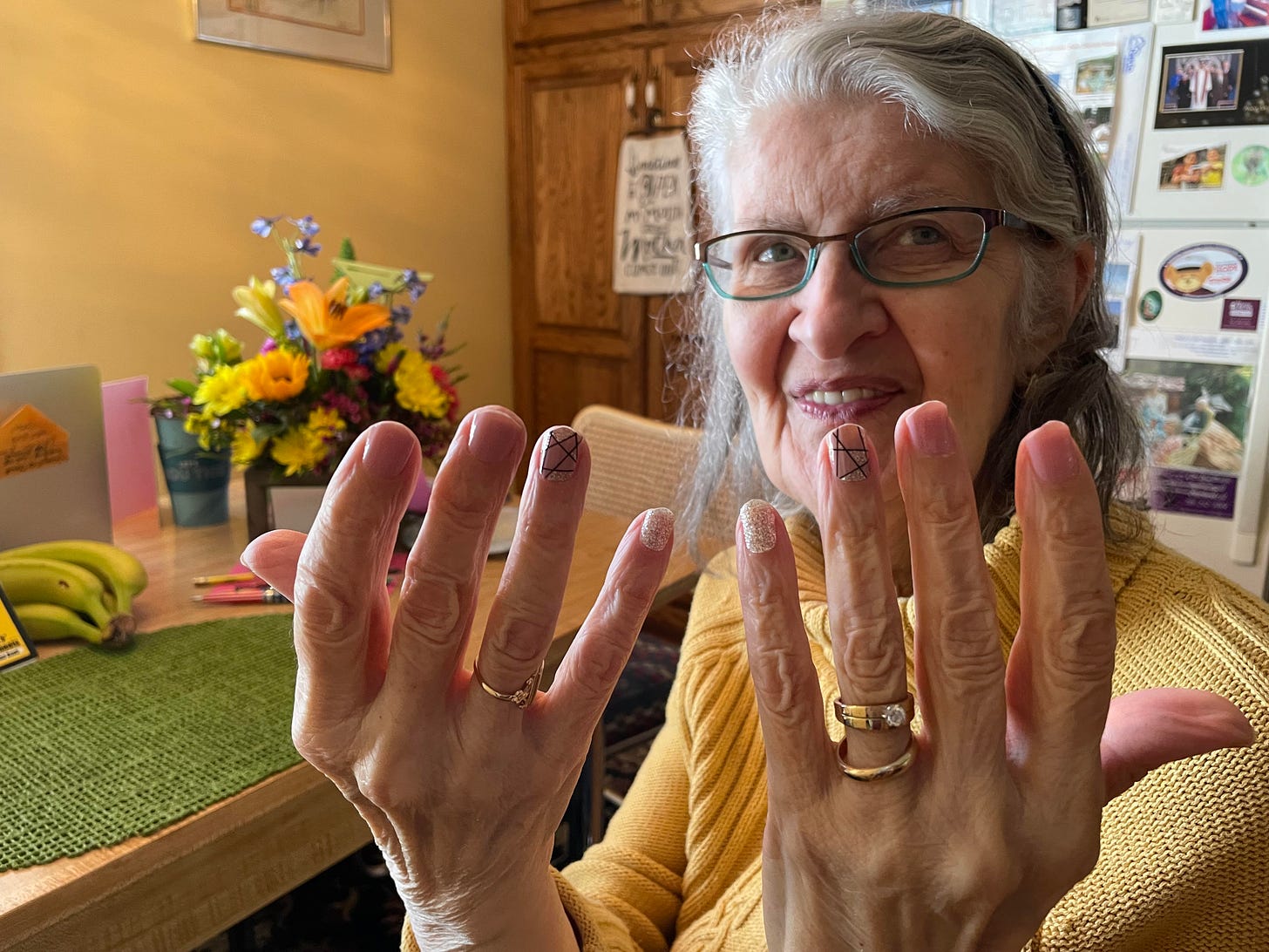 Mom at 80 showing off her freshly manicured fingernails, birthday flowers in the background