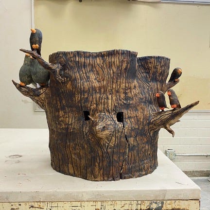 Ceramic tree stump mask with birds on branches in ceramic studio