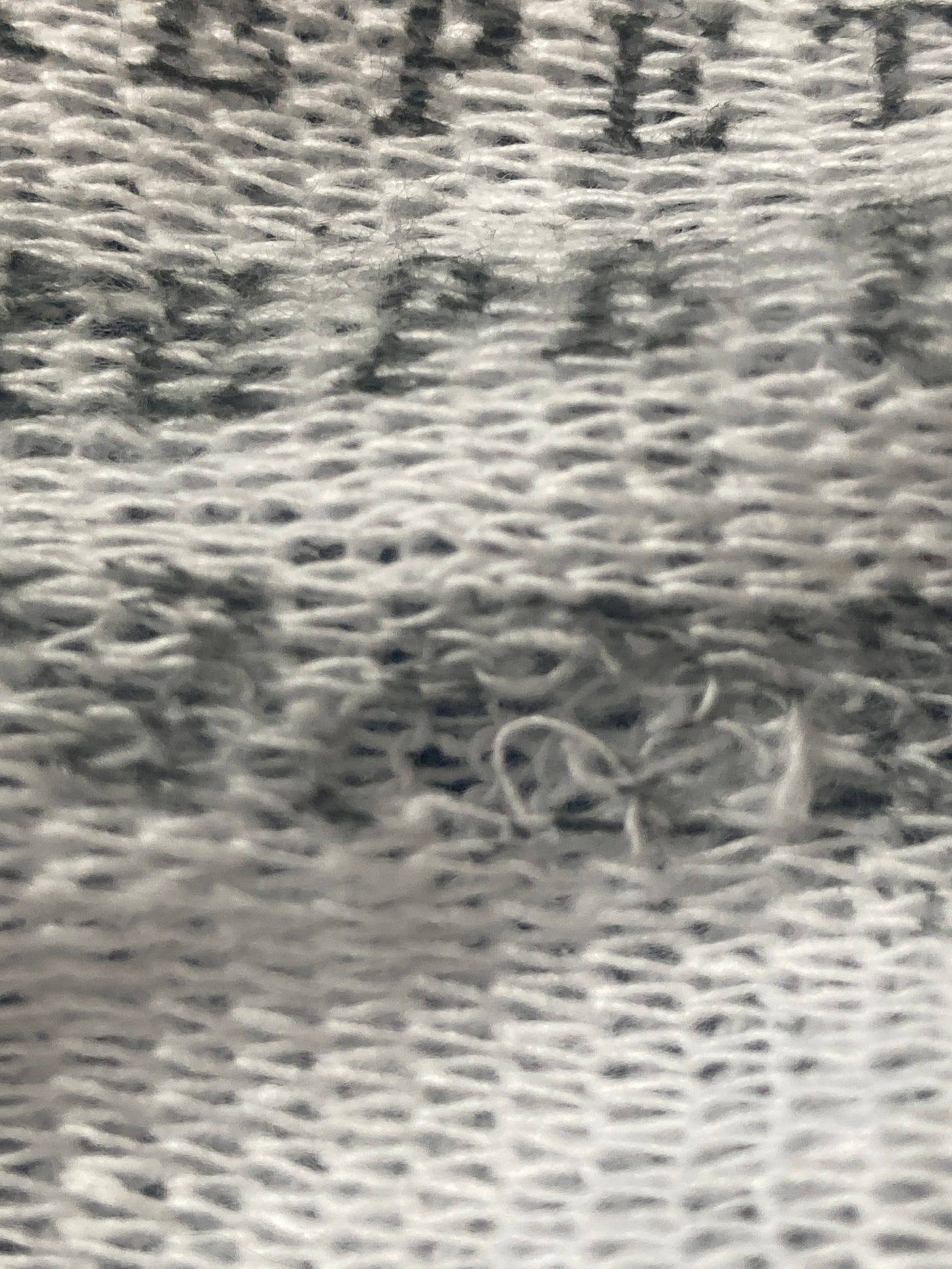 Detail of text printed on dishcloth with a frayed patch of wear and tear beneath the word ‘repetitive’