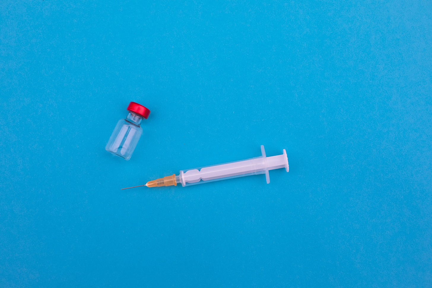 Hypodermic needle next to a vial for containing vaccine.