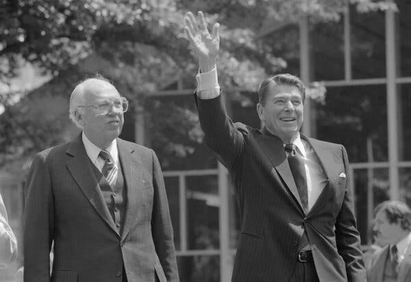 William J. Casey with President Ronald Reagan, who is smiling and waving. Both are wearing suits. 