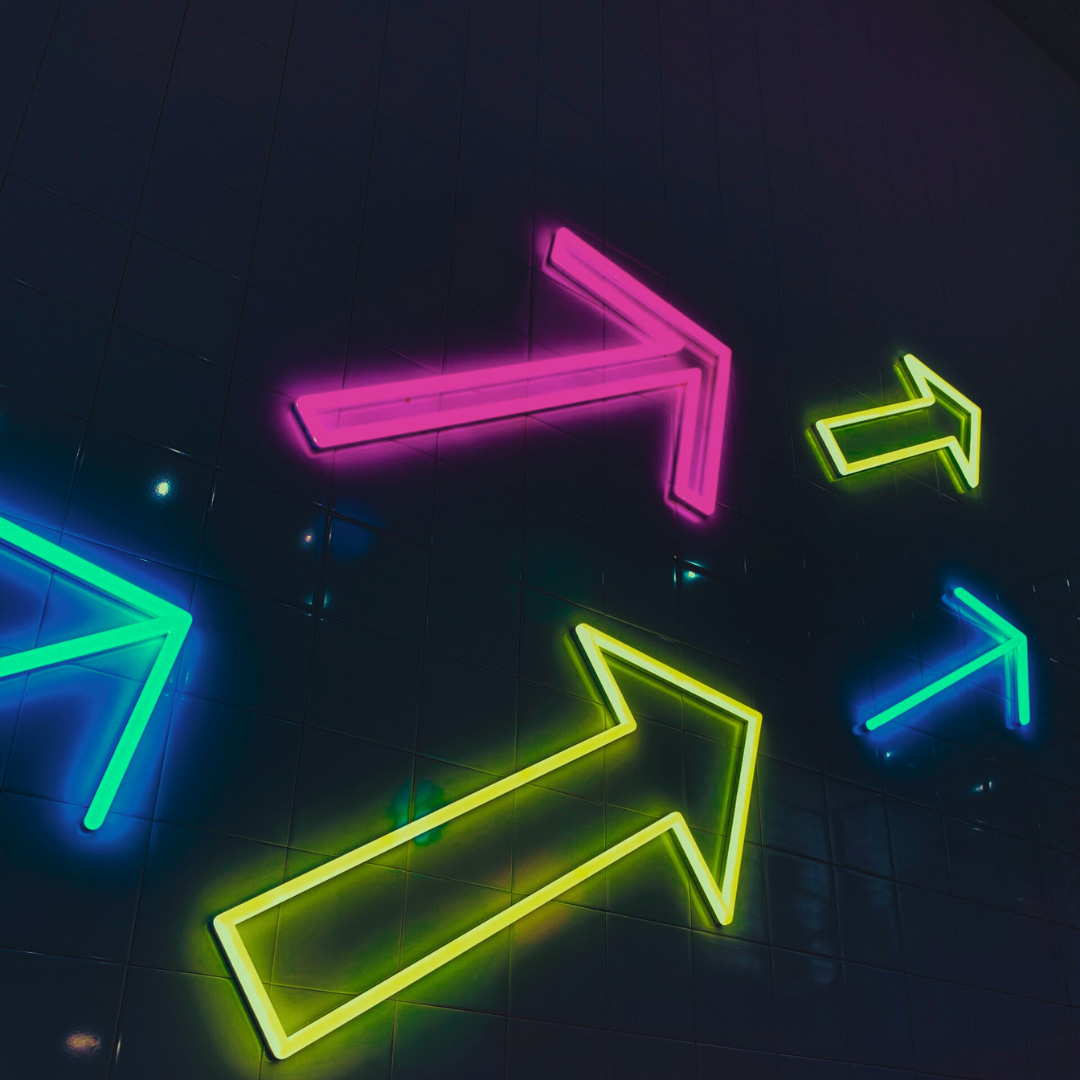  On a floor-to-ceiling black-lit wall, bright neon lights shaped like arrows point up and to the right.