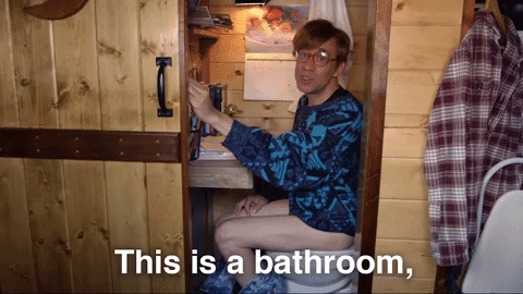 Gif de um homem sentando em um espaço minúsculo, quase um armário, dizendo "Isso é um banheiro e um espaço de home office"