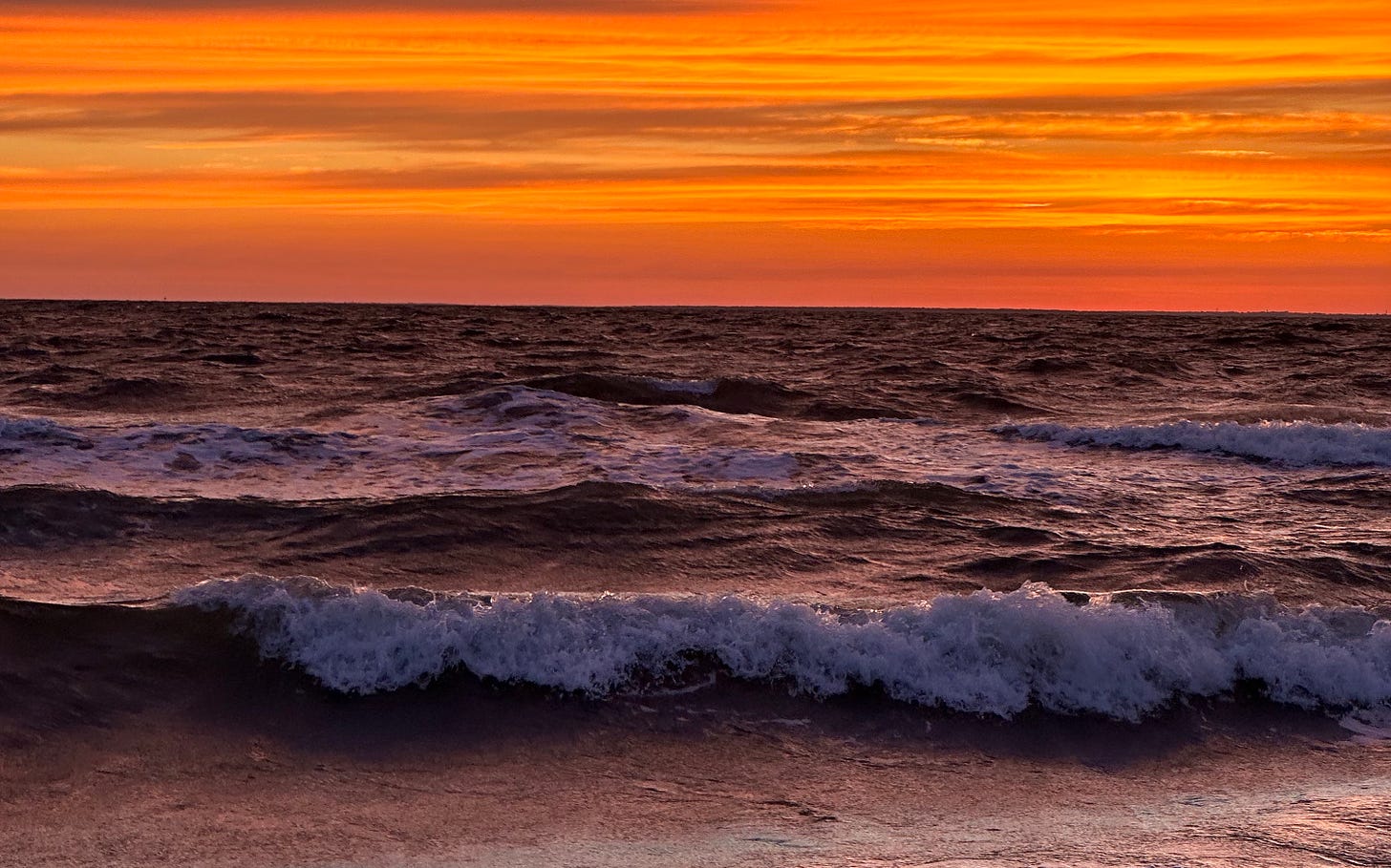 a very orange and red sunset on the beach